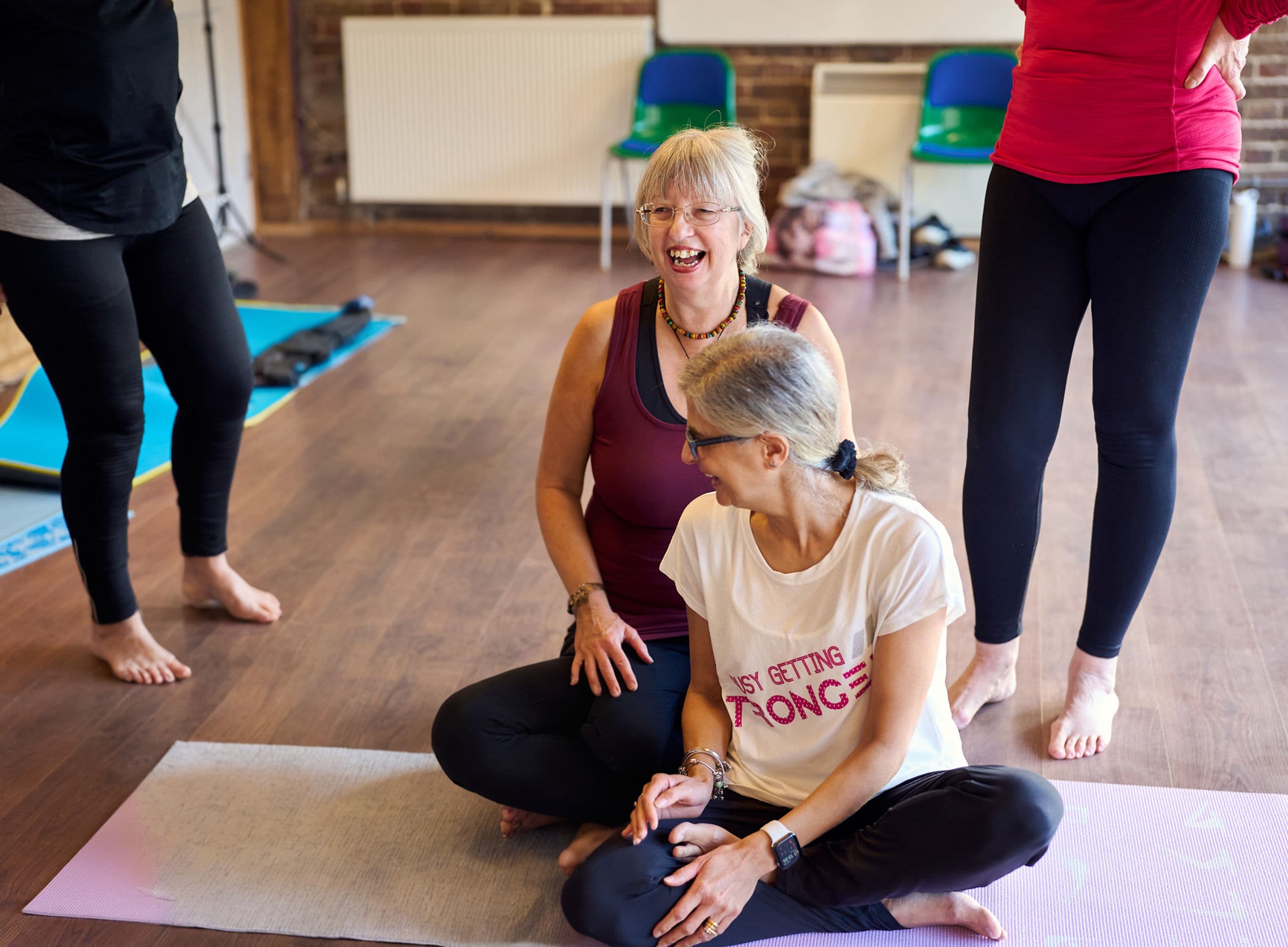 Two members laughing together in a yoga class